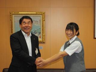 教育長と握手しながら記念撮影する女子生徒の様子。