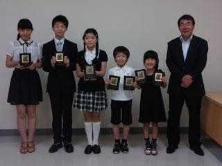 両手に賞状を持っている子供5人と教育長が記念撮影をした写真