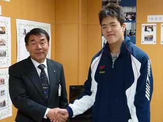 教育長と握手をする水泳大会出場の男子高校生の写真