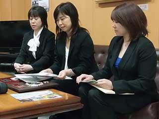 資料を手に報告をする小学校PTA広報委員会のメンバー女性3名の写真