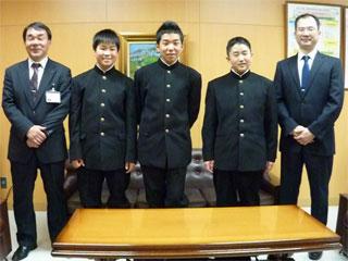 右から、スーツを着た男性と、3人の制服を着た男子生徒と、スーツを着た男性が並んでいる写真
