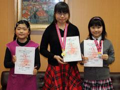 メダルと賞状を手に立つ3人の女子児童の写真