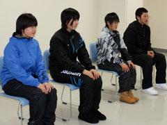 スキーウェアや学生服を着ている学生たちが座って並んでいる写真