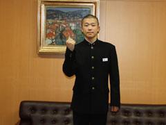 絵がかざってある部屋で男性がガッツポーズをして立っている写真