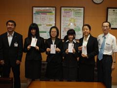 紙を手にした制服姿の女学生4人が立っていて、両脇に男性2人が立っている写真