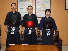 剣道着を着た三人の選手たちがテーブルの前に立っている集合写真
