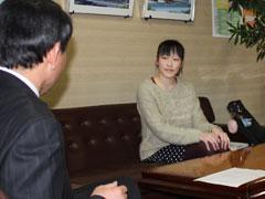応接室で、ソファーに座りながら男性と話をしている女生徒の写真