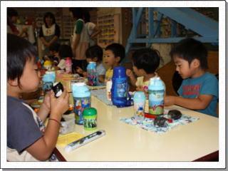 幼稚園の机に向かい、美味しそうにお弁当を食べる男の子たちの写真