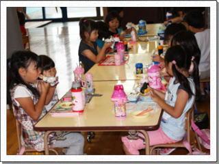 幼稚園の机に向かい、美味しそうにお弁当を食べる女の子たちの写真