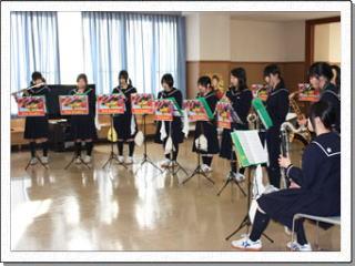 横一列に並びそれぞれの木管楽器を手にして演奏している女子生徒たちの様子の写真