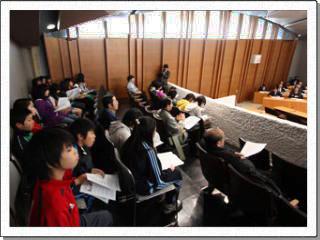 議席を見下ろす傍聴席の中で、資料を手に並んで座っている生徒たちの様子の写真