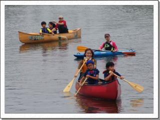 赤色と黄色のカヌーに2名の児童と1名の大人がそれぞれ乗ってカヌーを漕いでいる写真