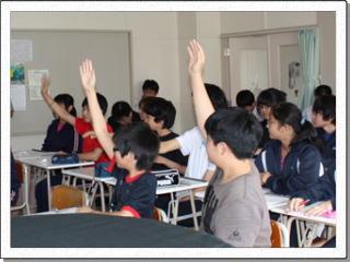 教室で着席している生徒たちの中で、3名の生徒が質問をするために手をあげている写真