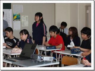 教室で着席している生徒たちの中で、1名の女子生徒が立って発言をしている写真
