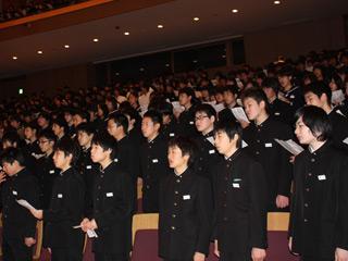 中学校の生徒たちが客席で立ち、合唱している様子の写真