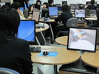 パソコンのディスプレイに映し出された先生の手元を見ている生徒の写真