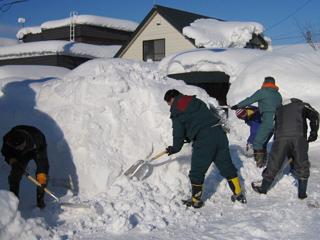 スコップを持ち、足元に散乱した邪魔な雪を掻き出している4人の男性の写真