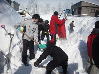 数人の生徒たちがスコップを使って雪を次々とかき分けている様子の写真