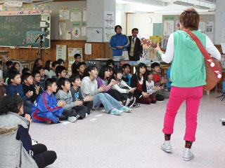 ギターを持って立って歌っている翔太さんと、床に座って手をたたきながら歌っている子どもたちの写真