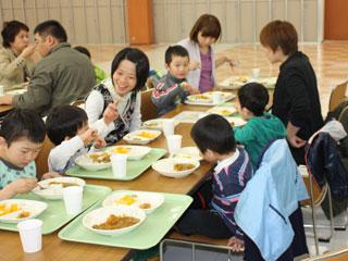 長机に座り、家族と一緒に食事を楽しむ子どもたちの写真