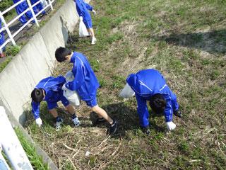 段差の脇にあるゴミを丁寧に拾っている3人の青いジャージを着た生徒たちの写真