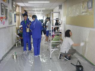 学校の廊下に白いペンキを塗る、ジャージ姿の生徒たちの写真