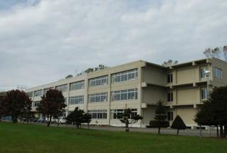 きれいに整備された芝生の前に建つ岩見沢市立豊中学校の外観の写真