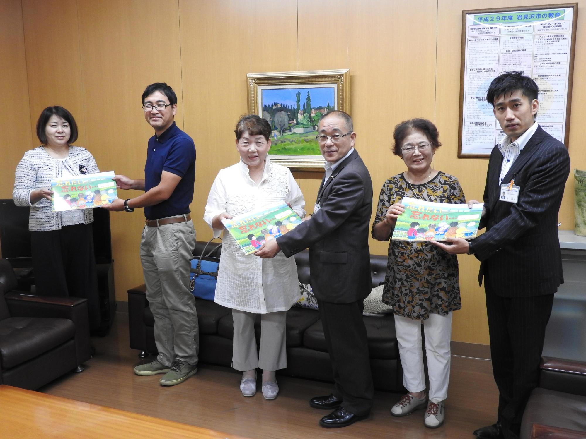 室内で男性一人と女性一人が組になって、計3組がそれぞれ絵本を持っている写真
