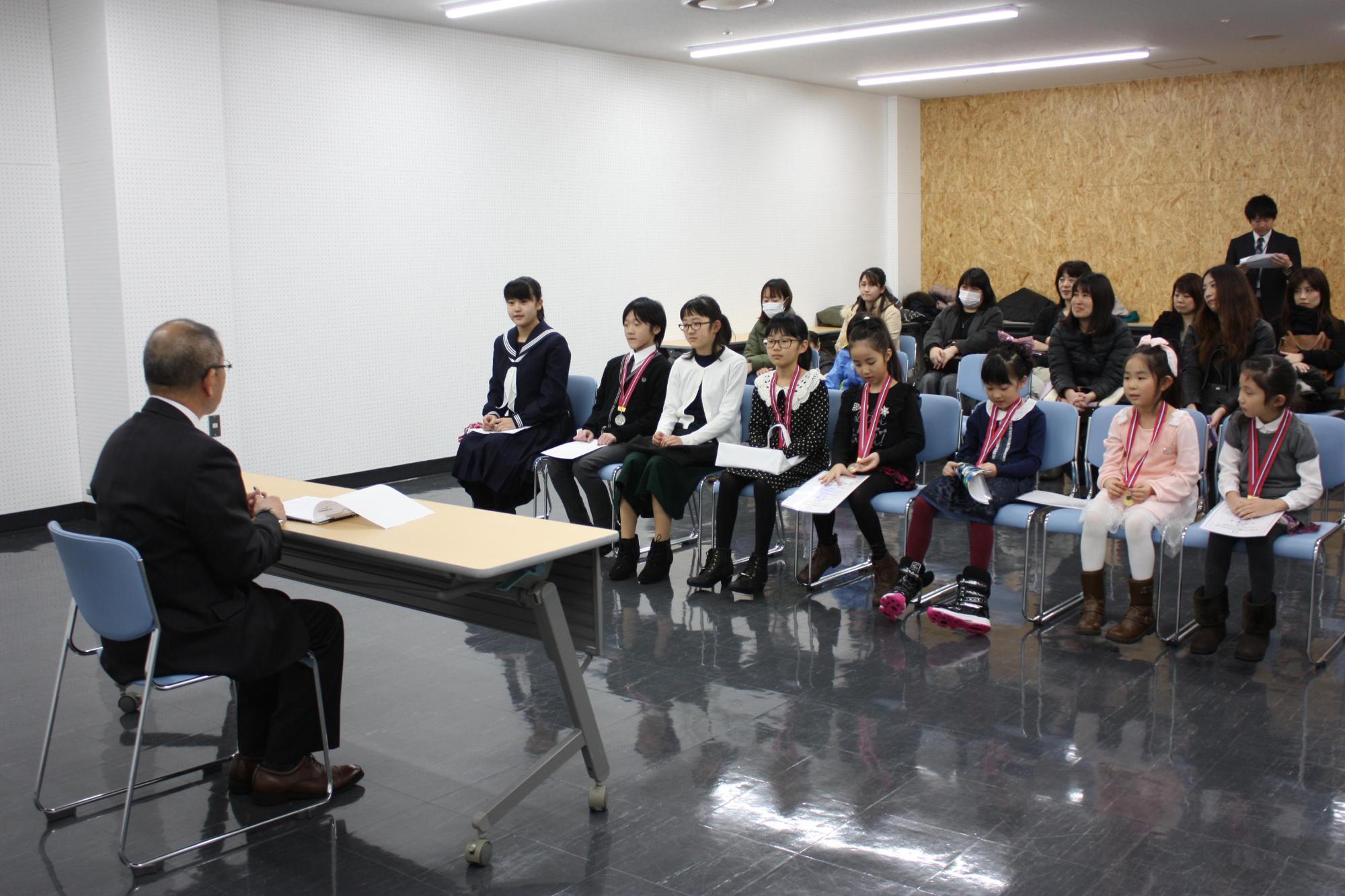 アジア大会に出場された子供たちが教育長と向き合って椅子に座っている写真