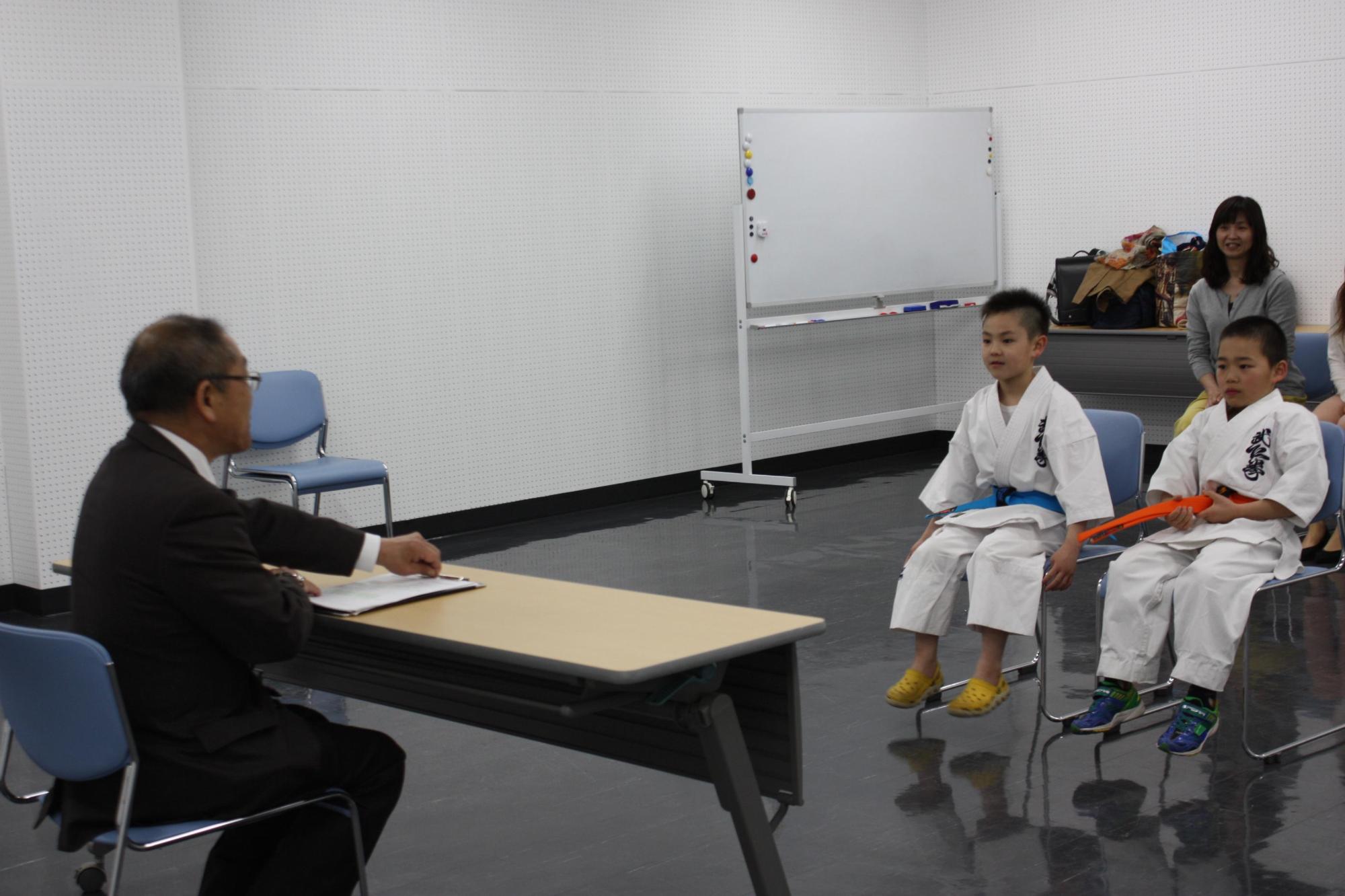 空手道着を着て教育長を表敬訪問する男子小学生2人の写真
