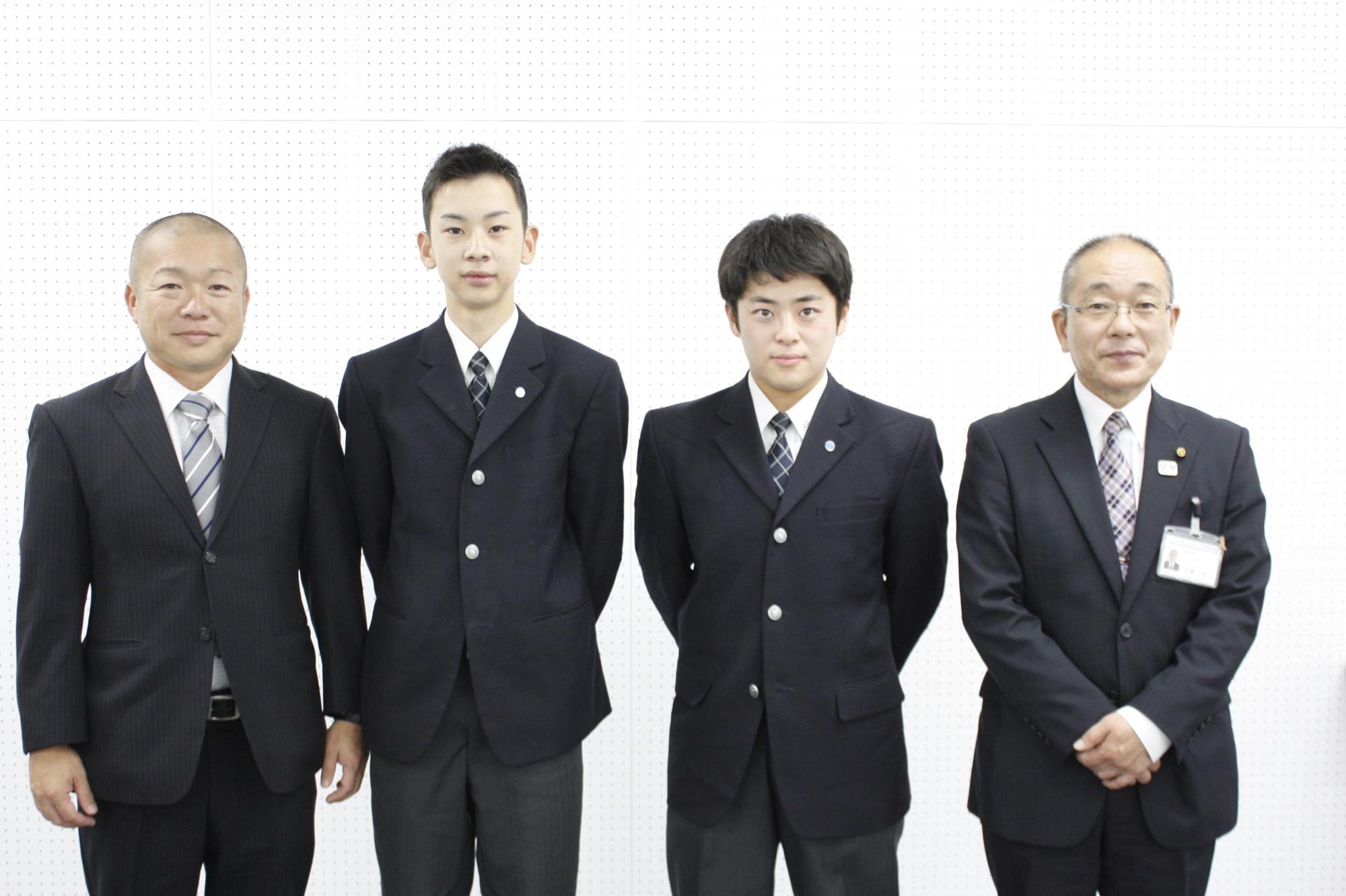 教育長と並んでいる男子ソフトボールの選手二人と関係者の写真