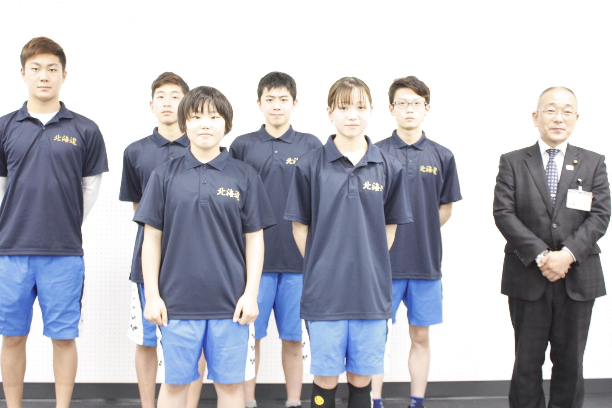 教育長と並んでスイミングスクールの少年少女6人が立っている写真