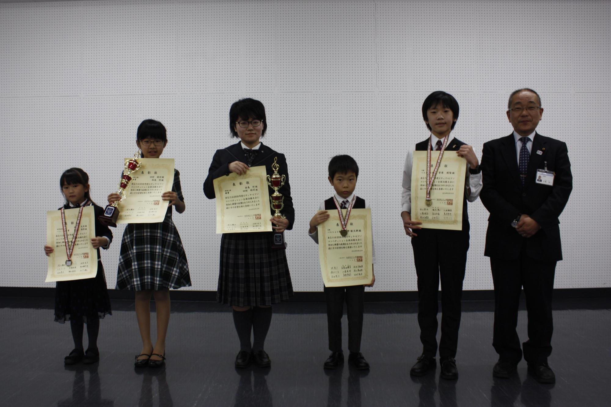 銀賞やベスト賞を受賞した賞状を手に教育長と記念写真を撮るメンバーたちの写真
