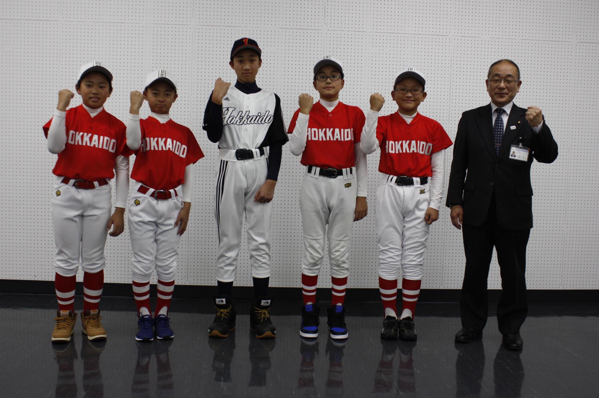 教育長と野球の大会に出る学生たちが並んで写っている写真