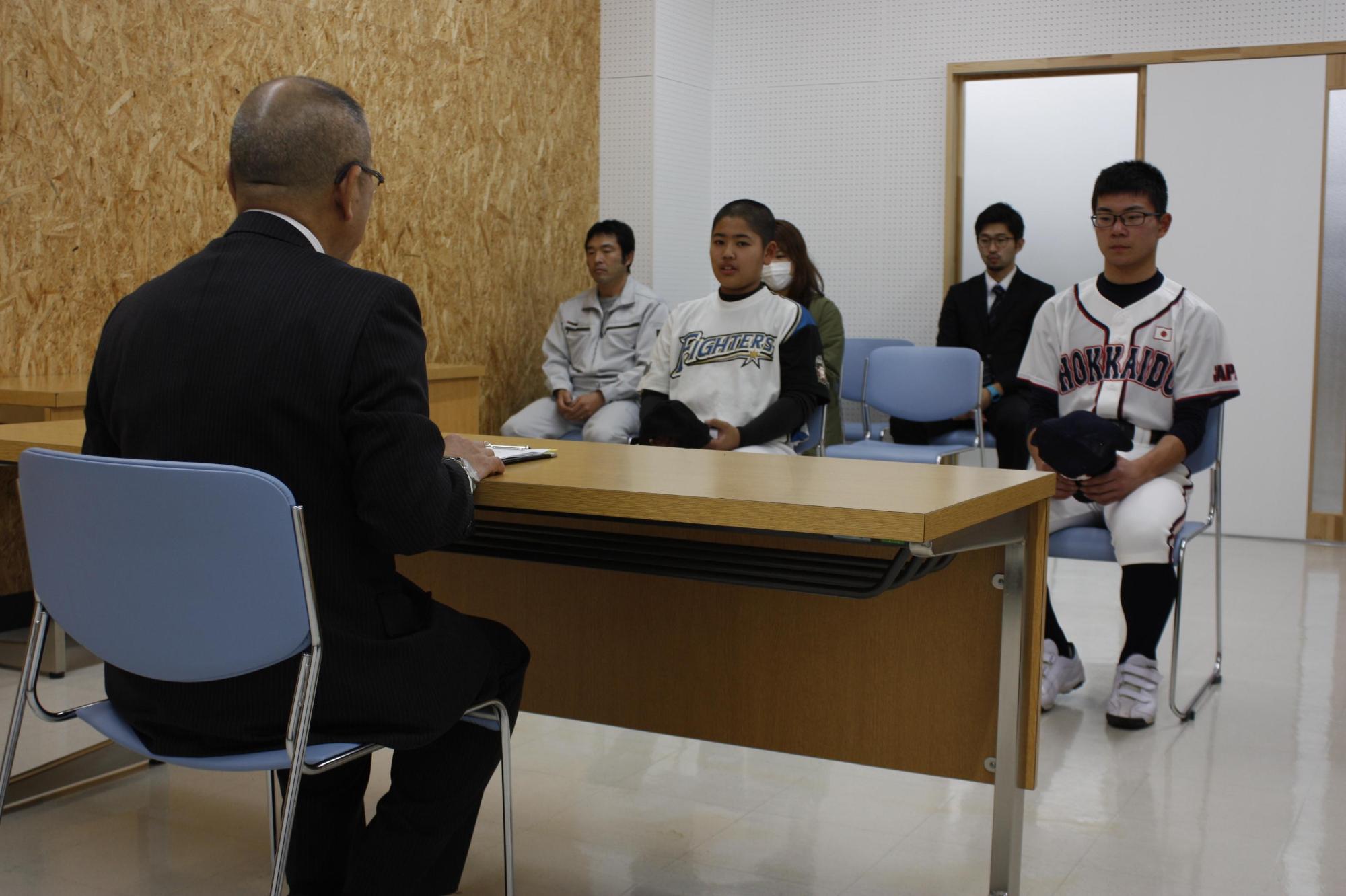 教育長と野球の選手たちが机を挟んで対面している写真