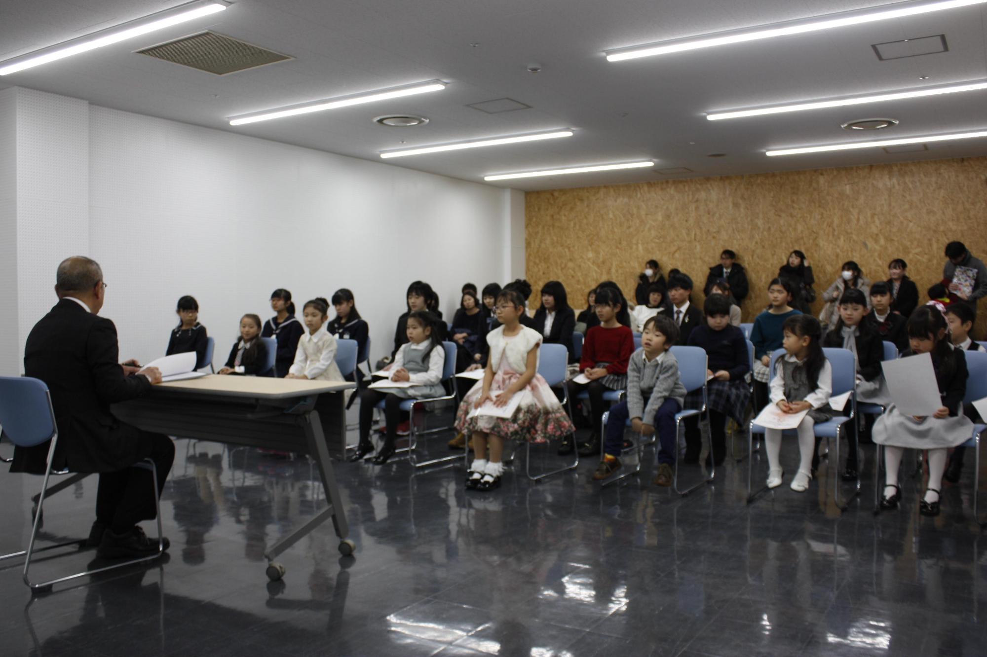 教育長とピアノのコンクールに出る学生たちが机を挟んで対面している写真