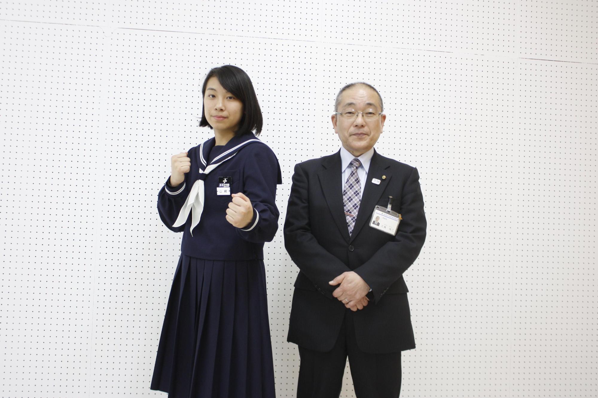 教育長の横でボクシングの構えをする女子学生の写真