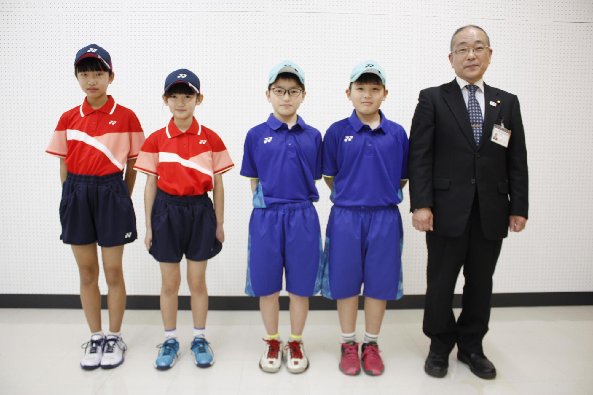 教育長の横でテニスのユニフォームを着た児童たちの写真