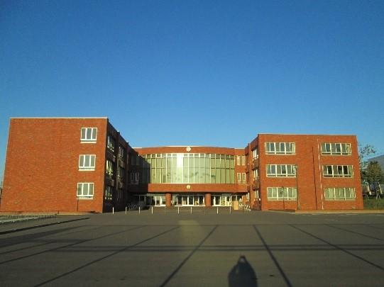 青空の下にどっしりと建っているレンガ色の岩見沢市立東光中学校の外観の写真
