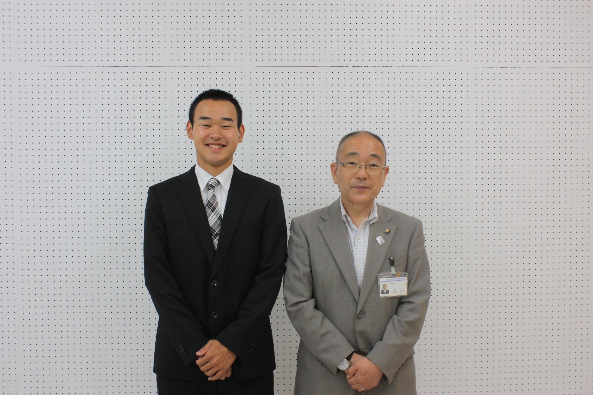 右からスーツを着た男性とスーツを着た男子生徒が並んでいる写真