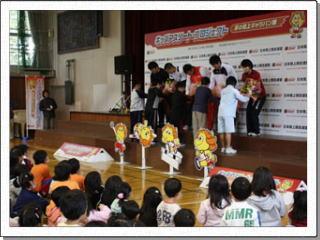 南小学校に来られた日本陸上競技選手の方々一人ひとりに児童が花束を渡している写真