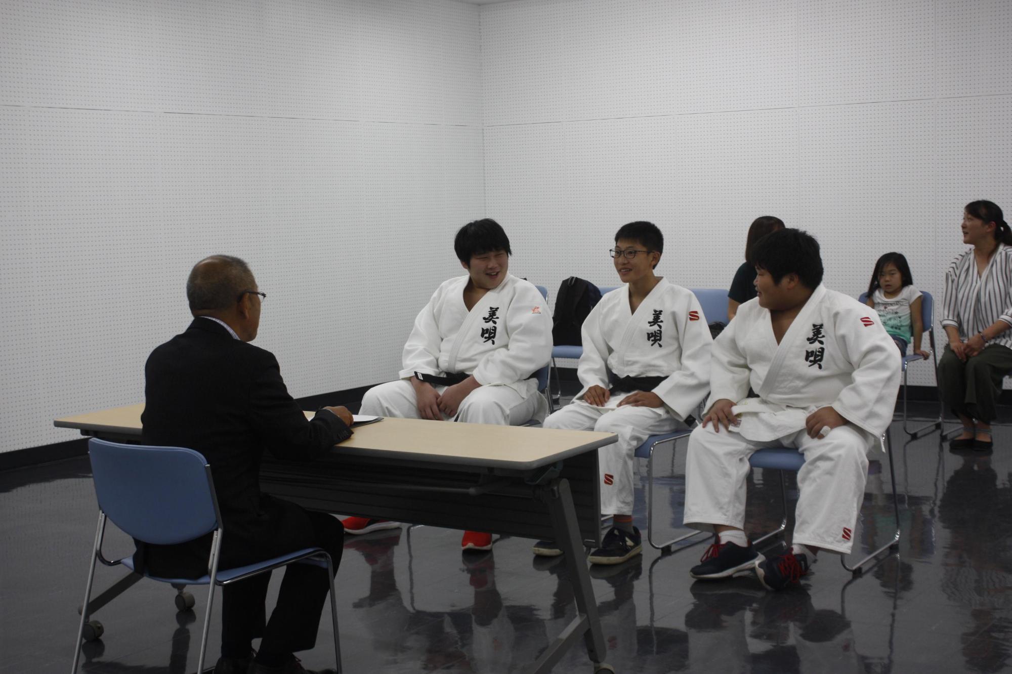 美唄市少年柔道会スポーツ少年団の3名と歓談している様子の写真