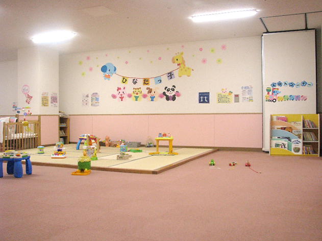 カラフルなイラストで飾られた壁と、たくさんのおもちゃがある親子ひろばの写真