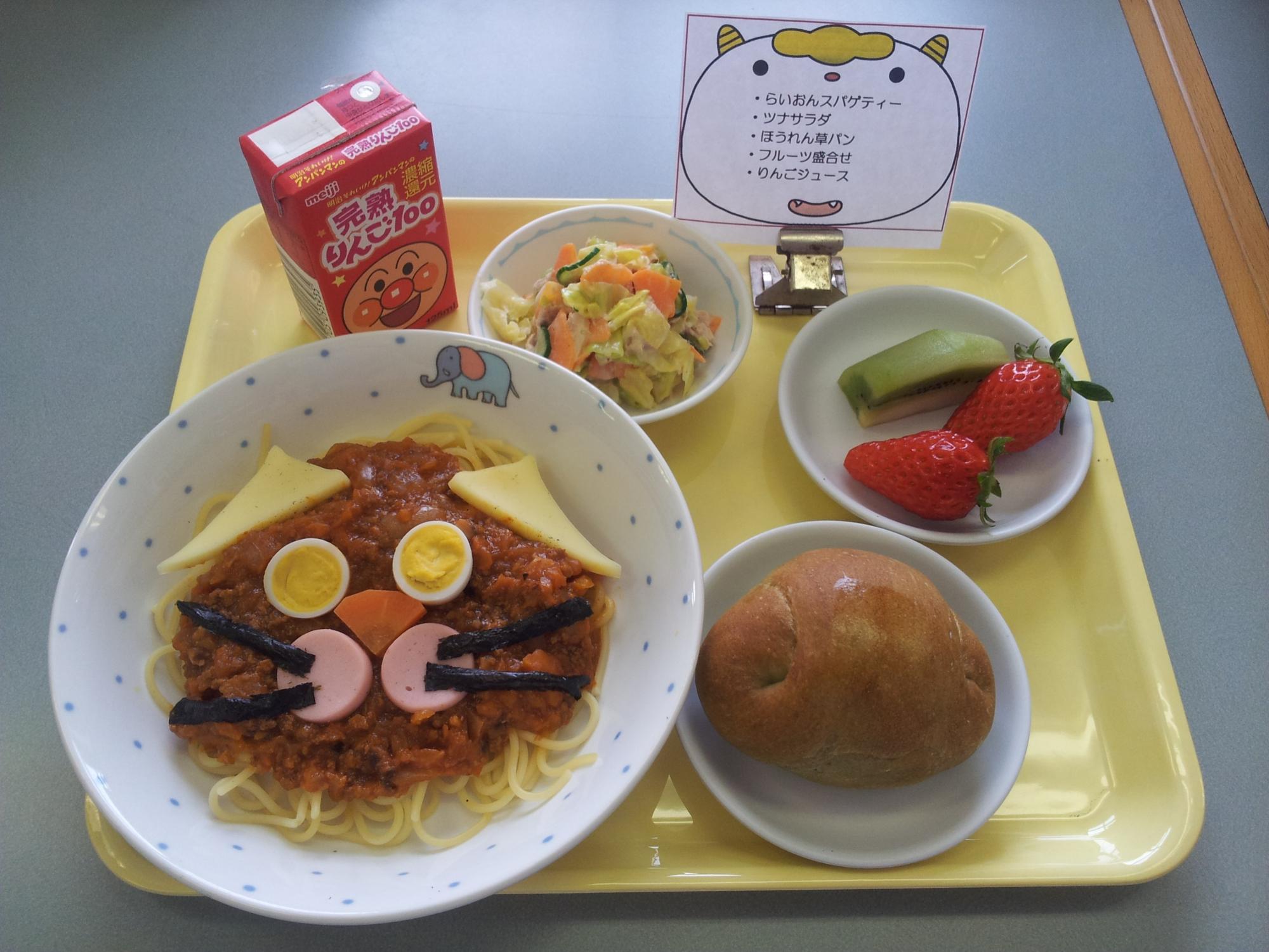 かわいいライオンの顔を表現したスパゲティとほうれん草味の小さなロールパンとツナサラダ、くだもののキウイと真っ赤なイチゴと紙パックのアンパンマンの小さなリンゴジュース