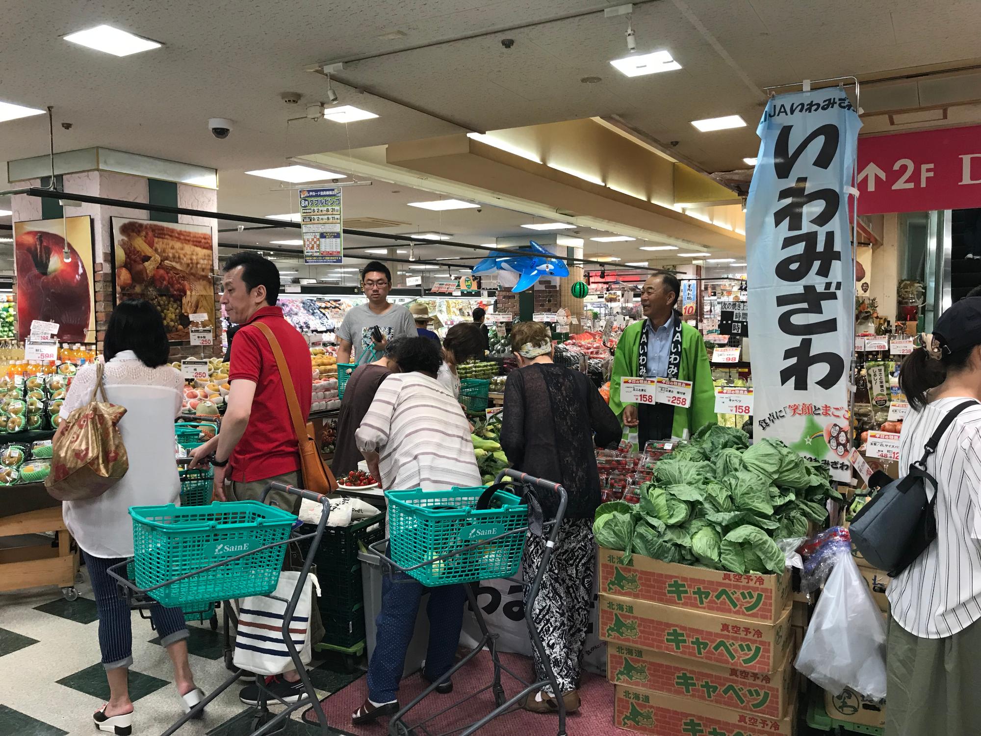 男性が持っている食材を、三角巾とエプロンをした子供たちがのぞき込んでいる写真