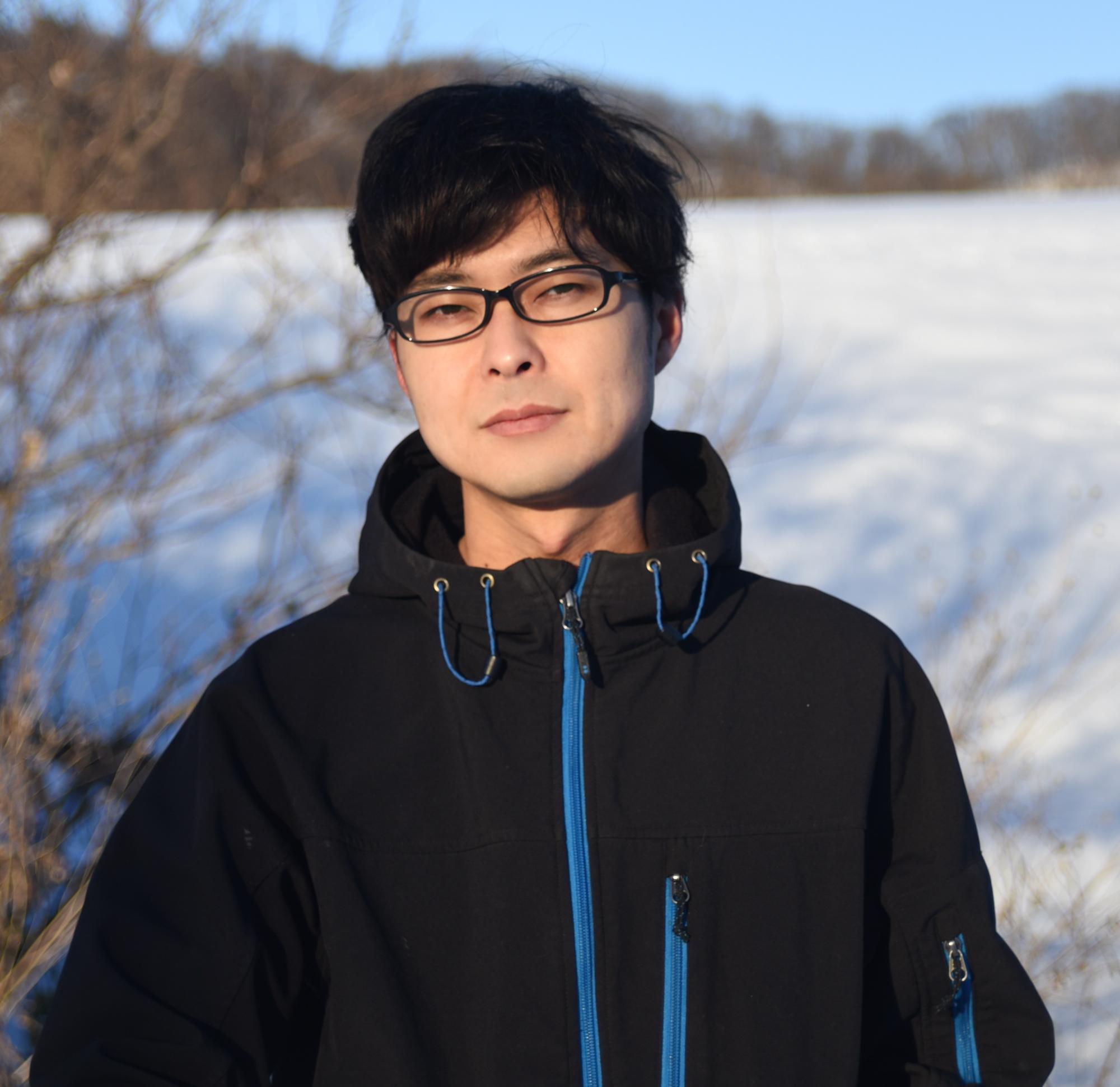 雪山の前で黒いジャンパーを着た柴田さんの写真