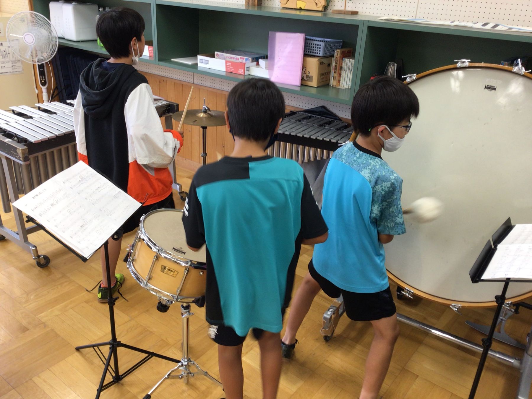 教室にある太鼓やシンバルなどの楽器を練習している、3人の男の子の写真