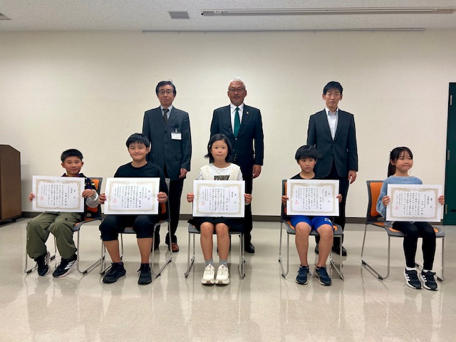 岩見沢市子ども発明工夫展の表彰式における受賞者と審査員の写真